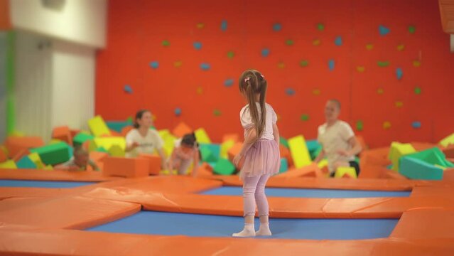 Children having fun on trampoline in entertainment center, childhood and sporty lifestyle. Girl in leisure sport center for kids. Active leisure. 