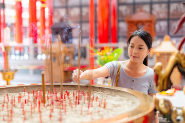 Woman offer incense stick to god in Chinese temple