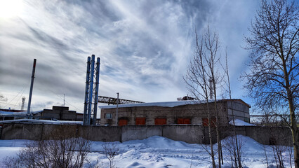Fototapeta na wymiar Abandoned Industrial Buildings in winter day and sky with white clouds on Background
