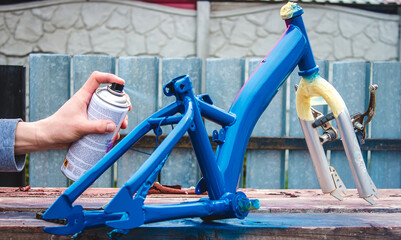 a man paints a bicycle with spray paint.