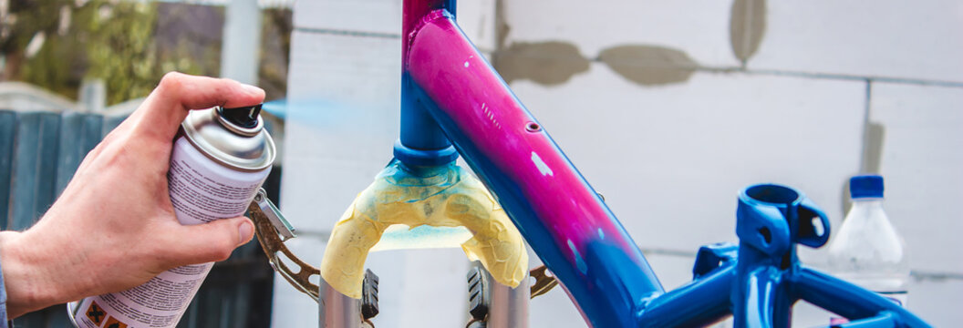 a man paints a bicycle with spray paint.