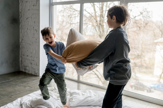 Playful brothers pillow fighting at home