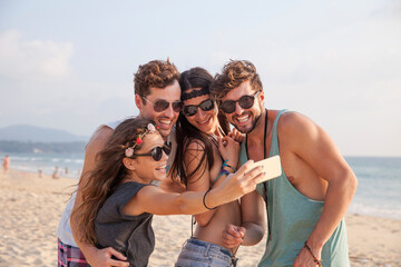 Happy woman taking selfie with friends on vacation at beach