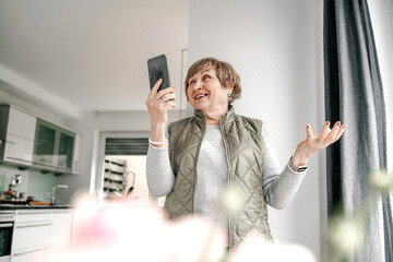 Elderly woman doing video call through smart phone at home