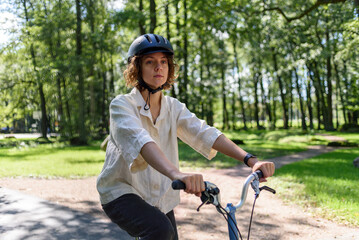 Fototapeta na wymiar Young woman in helmet riding on bicycle at park