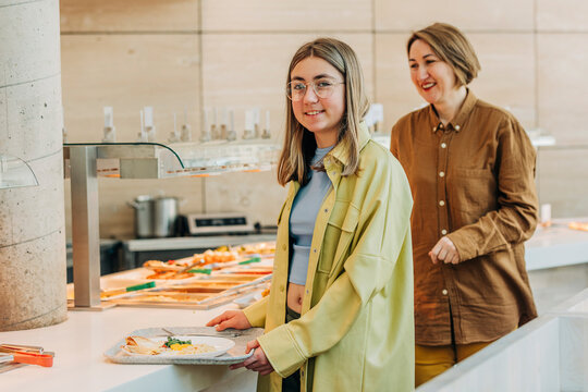 Smiling mother and daugther taking food at buffet in cafe