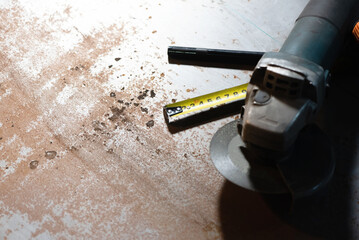 Construction meter tape, marker and angle grinder close up background.