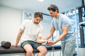 Obraz premium Male patient sitting on a couch and exercising his arm