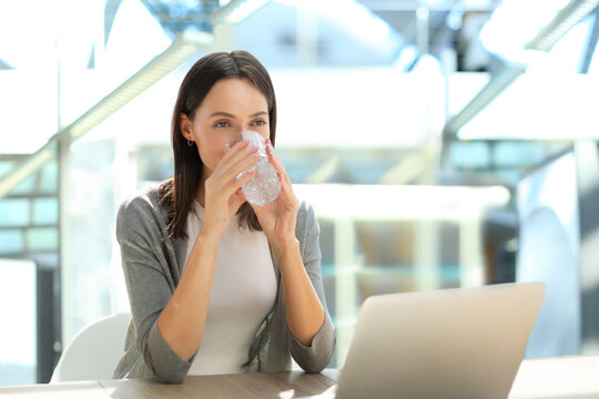 Woman drinking water after taking medicine in the office