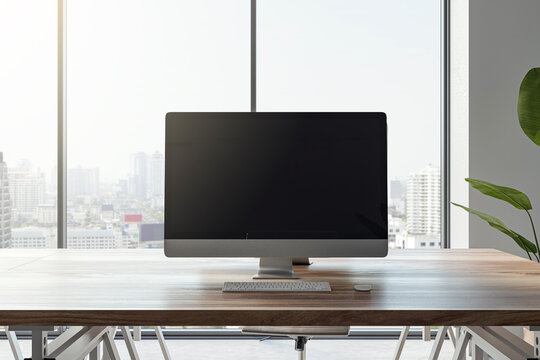 Front view of a modern office workplace with wooden desk with blank screen computer, on city view window background in light interior, mockup. Comfortable and ergonomic workspace concept. 3D Rendering