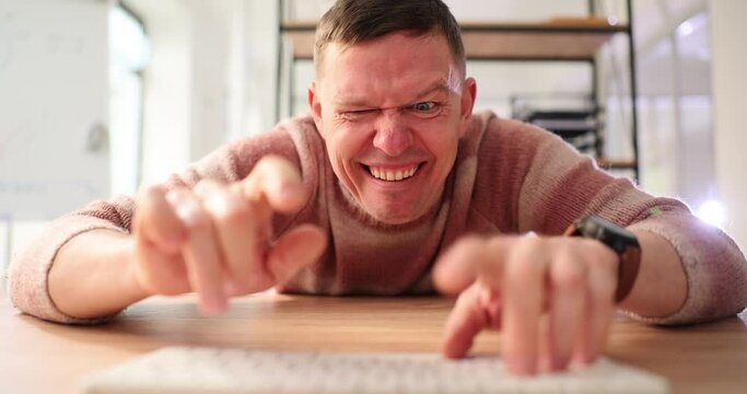 Funny and crazy man using computer uses Internet. Male hands on keyboard and psychopath writes message online
