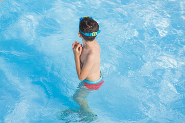 Elementary caucasian kid playing in the pool