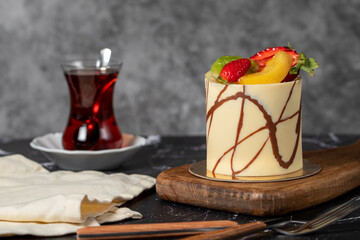 Cream cake covered with fruit and chocolate. Fruit cake on a dark background