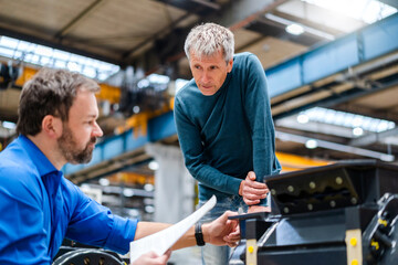 Businessman listening to manager explaining machinery at factory
