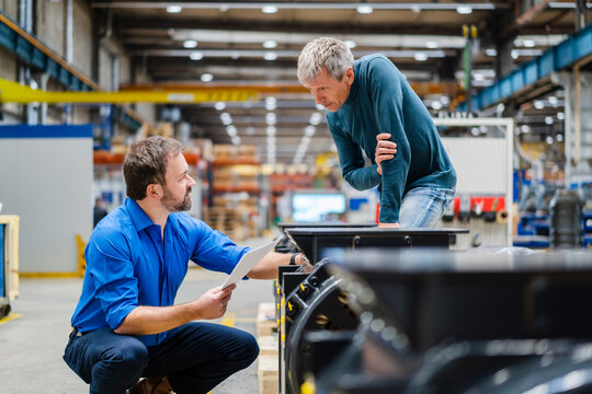 Manager discussing with manager over machinery at factory