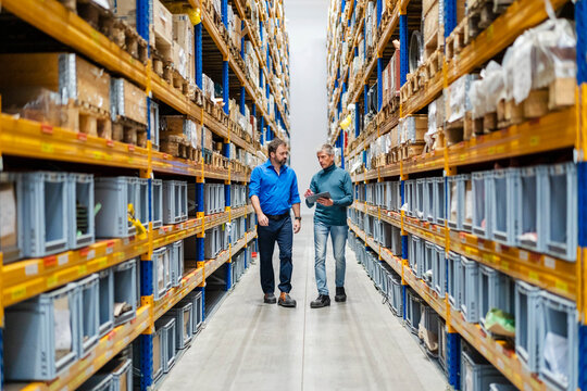 Businessman and manager walking between aisle in warehouse