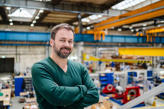 Smiling manager with arms crossed at factory