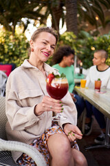 Vertical portrait of beautiful Ukrainian mature woman outside gathering with girlfriends in a bar, looking at camera smiling happily.