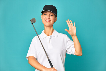 A young caucasian golfer woman smiling cheerful showing number five with fingers.