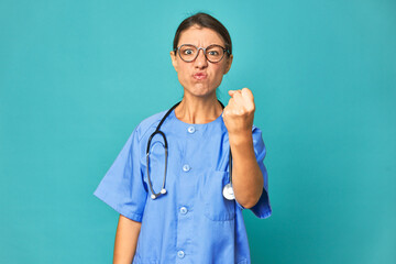 A young nurse woman isolated showing fist to camera, aggressive facial expression.