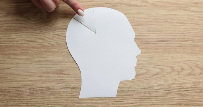 Female hand with paper human head and piece of brain. Neurology and logical thinking