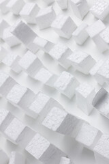 Texture formed by geometric pieces of white polystyrene randomly placed on a white surface.