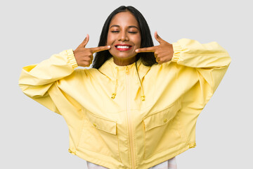 Young Indian woman cut out isolated on white background smiles, pointing fingers at mouth.