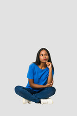 Young Indian woman sitting on the floor isolated on white background