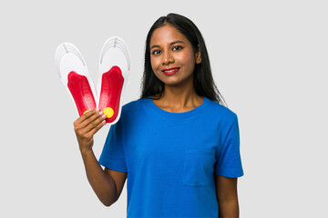 Young indian woman holding a foot insoles isolated on white background