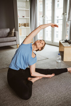 Young blonde woman practicing yoga in her apartment