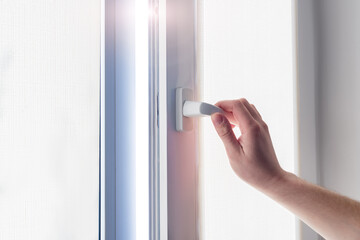 A man's hand holds a plastic window handle.Manual opening white plastic pvc window at home.A man...