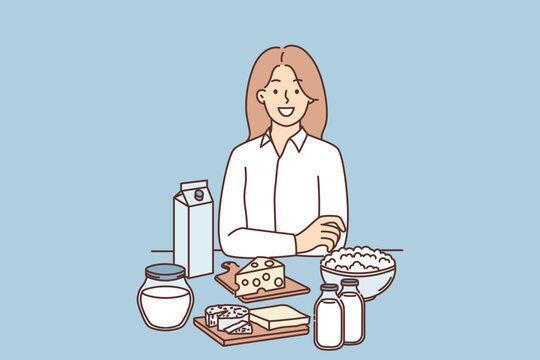 Woman is standing near table with dairy products and yogurt or cheese high in lactose and nutrients