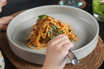 Little girl eating a portion of spaghetti bolognese at the restaurant	