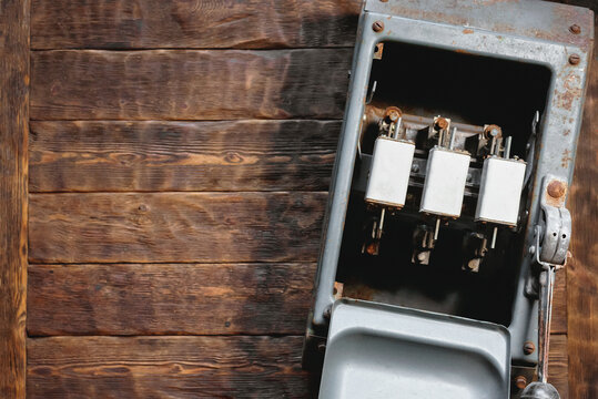 Electric works concept flat lay background with copy space.  Old open electric knife switch with fuses on the wooden workbench background