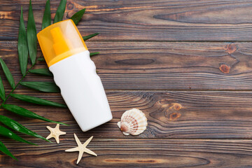 Fototapeta na wymiar Sunscreen spray bottle. Bottle with sun protection cream and sea shells with tropical green leaf on color background, top view