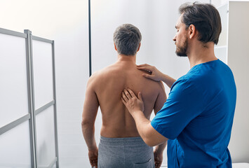 Standing male patient has his spine investigated by osteopath. Osteopath examination - 600366207