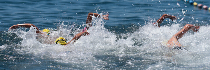 Group of swimmers children swim in the sea at the races. Swimming children in clean ocean water....