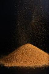 Falling unrefined cane sugar Panela on a black.