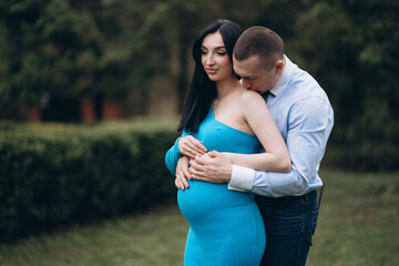 A young man kisses his pregnant wife in the stomach with care. place to copy