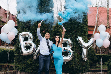 Young excited couple blowing up surprise balloon during gender reveal party.