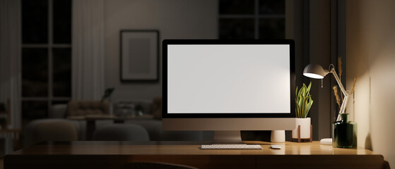Home workspace in a dark living room at night with computer mockup, table lamp