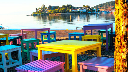 Fototapeta na wymiar Aegean town, Resort town, reflection and colorful authentic table and chairs in calm sea in early morning