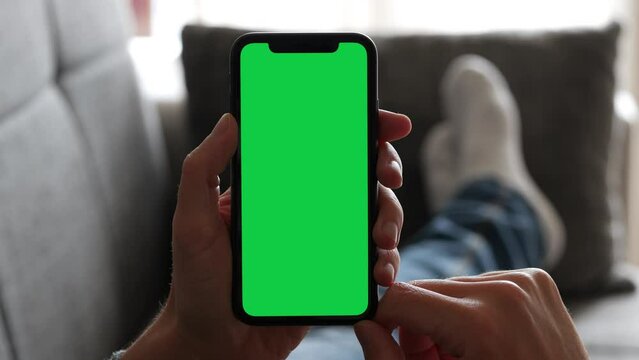Single Tapping and Holding a Green Screen Smartphone on the Couch at Home