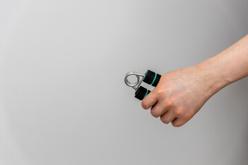male hand firmly gripping a hand gripper, representing the concept of strength, perseverance, and self-improvement. Hand grippers are commonly used by athletes and fitness enthusiasts to improve grip 