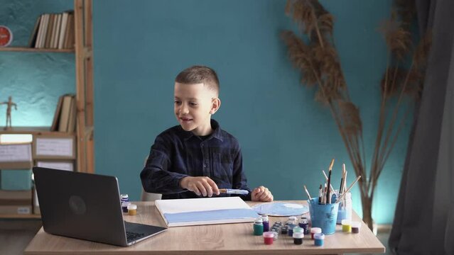 Online education of children. Schoolboy watching a video lesson call chat creative course art drawing using laptop at home.