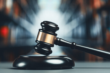 Focus wooden gavel hammer on blurred background of lawyer working or studying at library. Lawful...