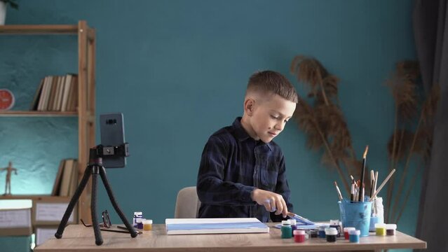 Schoolboy using smartphone for his homework, Child doing homework painting paints by lesson on cell phone searching information on internet. E-learning or Homeschooling education