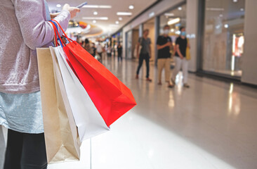 Woman holding many paper bags standing in spacious shopping mall. Shopping concept