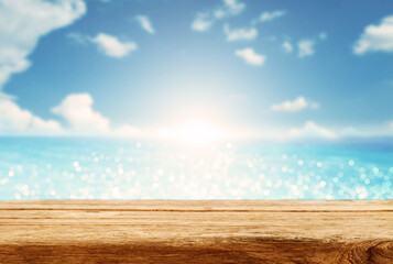 Empty wooden table are placed outdoors on spring sunny sky background with blue sparkling sea water and bokeh blurry. Counter display concept