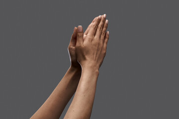 Female hands showing gesture of praying against grey background. Social issues, freedom of speech, equality. Concept of human relation, community, togetherness, symbolism, culture, communication